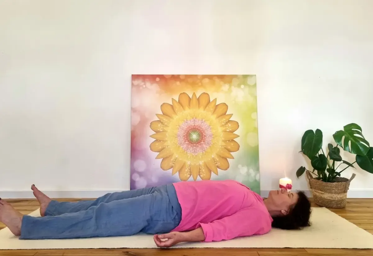 Eine Frau liegt entspannt auf der Matte im hellen Yoga-Nidra-Raum