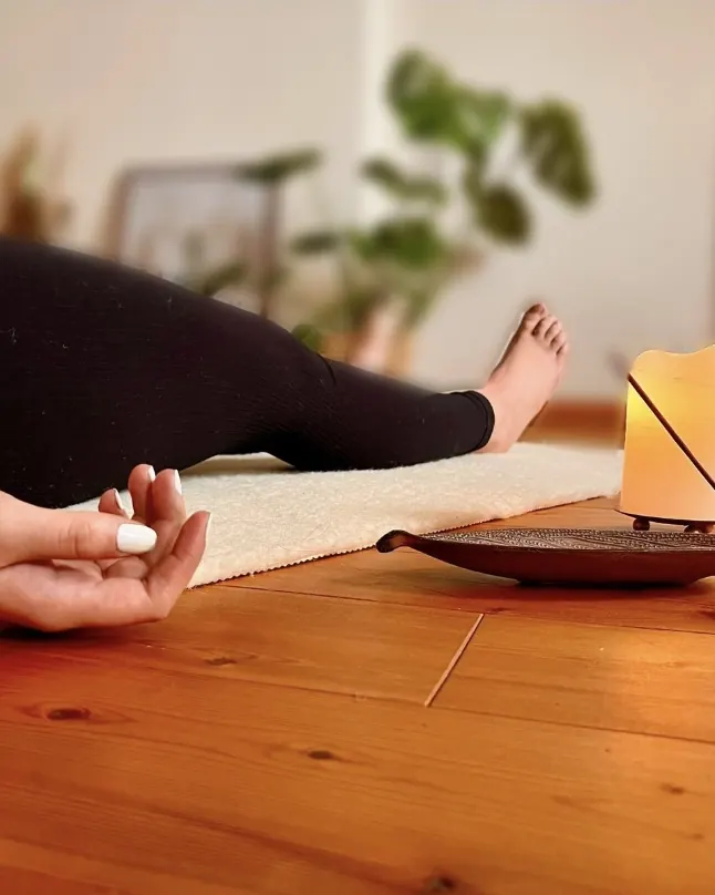 Entspannt liegende Hand auf der Matte, daneben eine Kerze